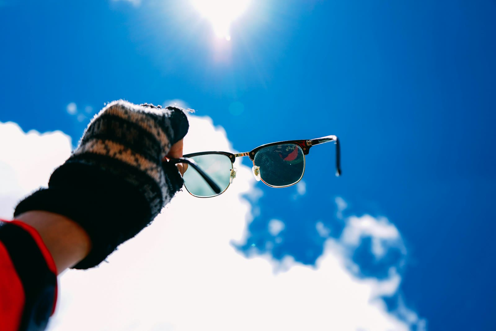person holding black framed Clubmaster-style sunglasses