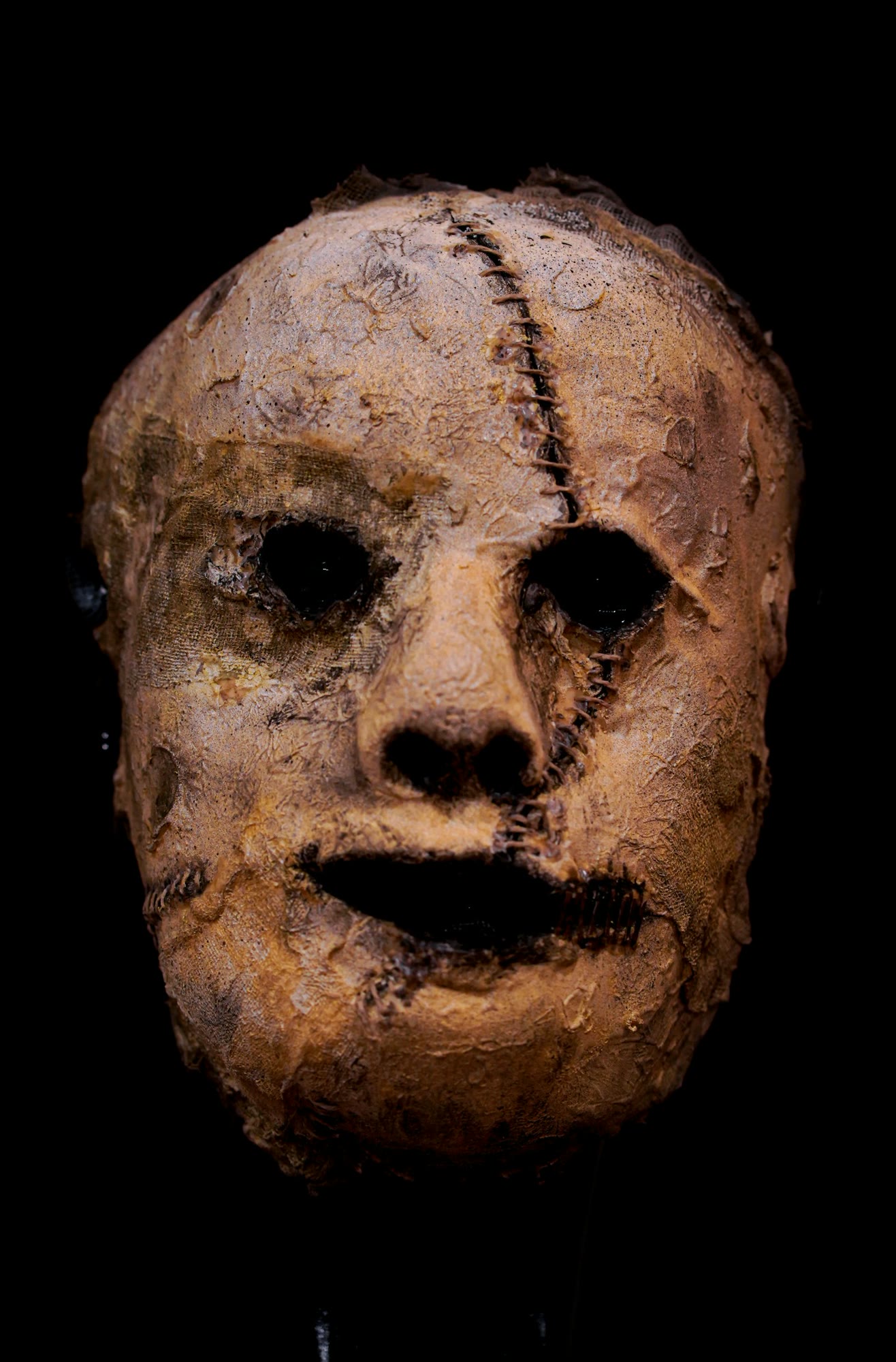 An old mask with a creepy face on a black background